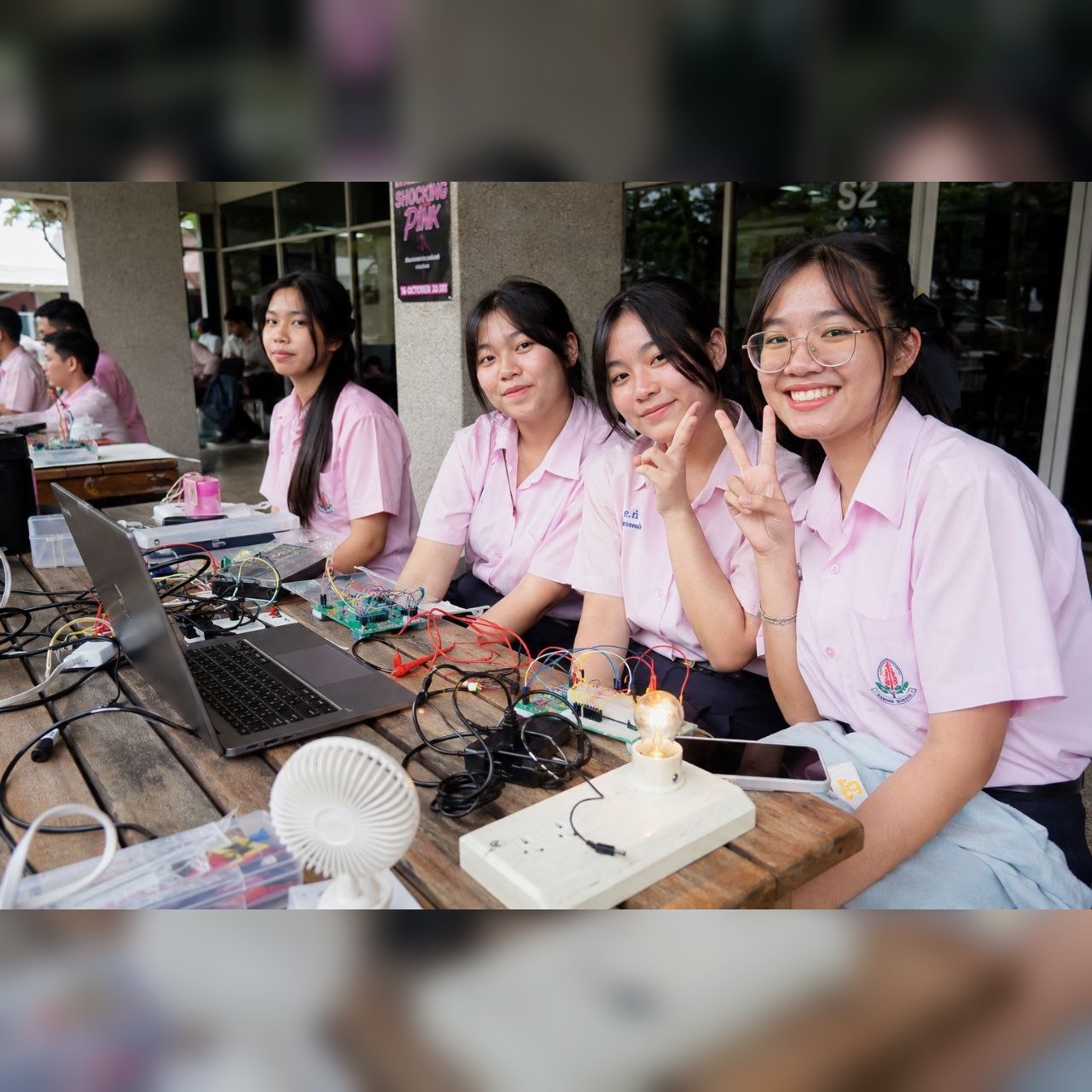 ทีมผู้เรียนทำโปรเจคอิเล็กทรอนิกส์บนโต๊ะพร้อม laptop วงจร และพัดลมทดลอง